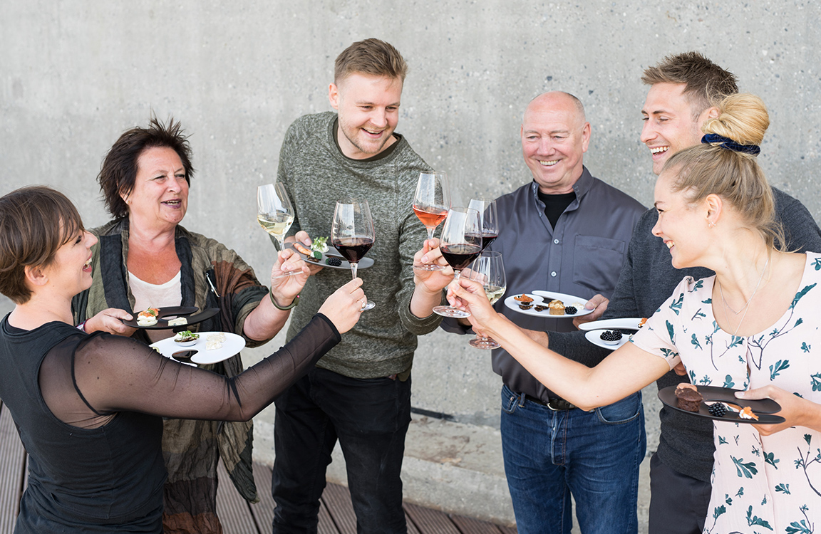 family and friends enjoying their time together, while holding plates with a hole for the wine glass